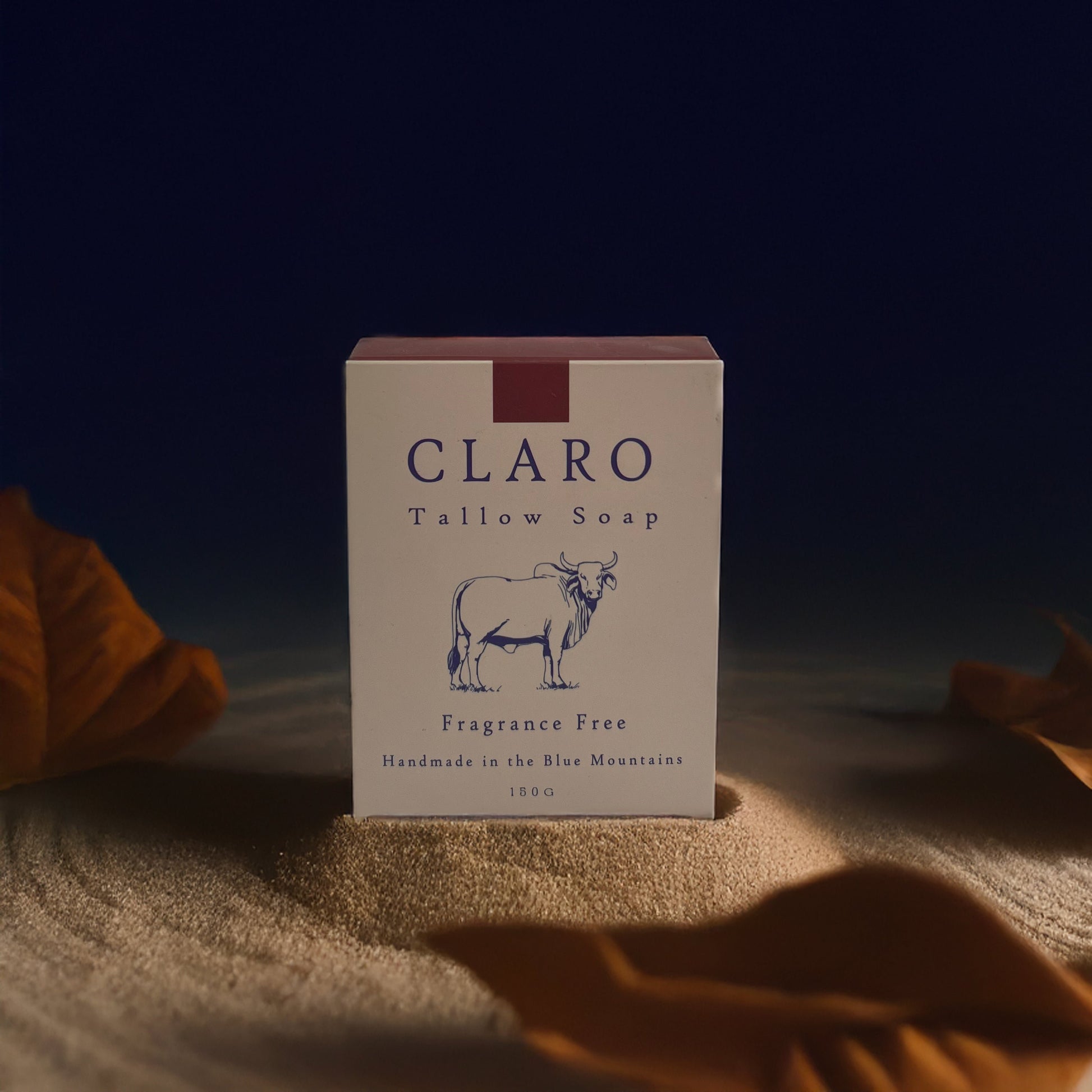 Claro Tallow Soap box on sand, with minimalist packaging featuring an illustrated bull, labelled as fragrance-free and handmade in the Blue Mountains