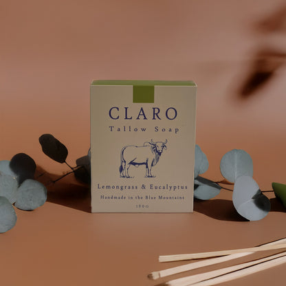 Claro Tallow Soap box labeled 'Lemongrass & Eucalyptus,' surrounded by eucalyptus leaves and wooden sticks on a soft, beige background.