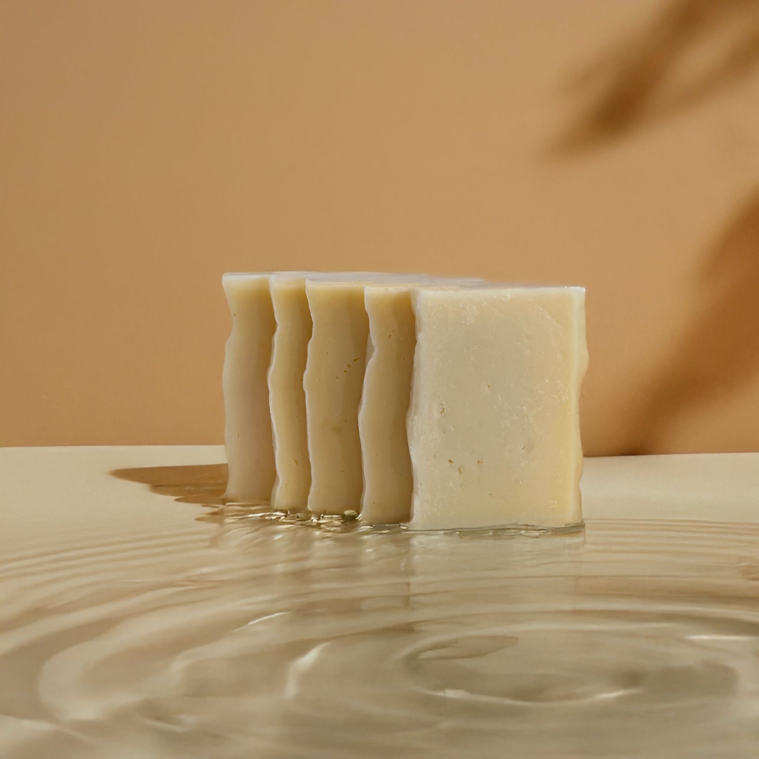 Bar of Claro soap standing on a smooth surface with rippling water in the foreground, set against a warm beige background.